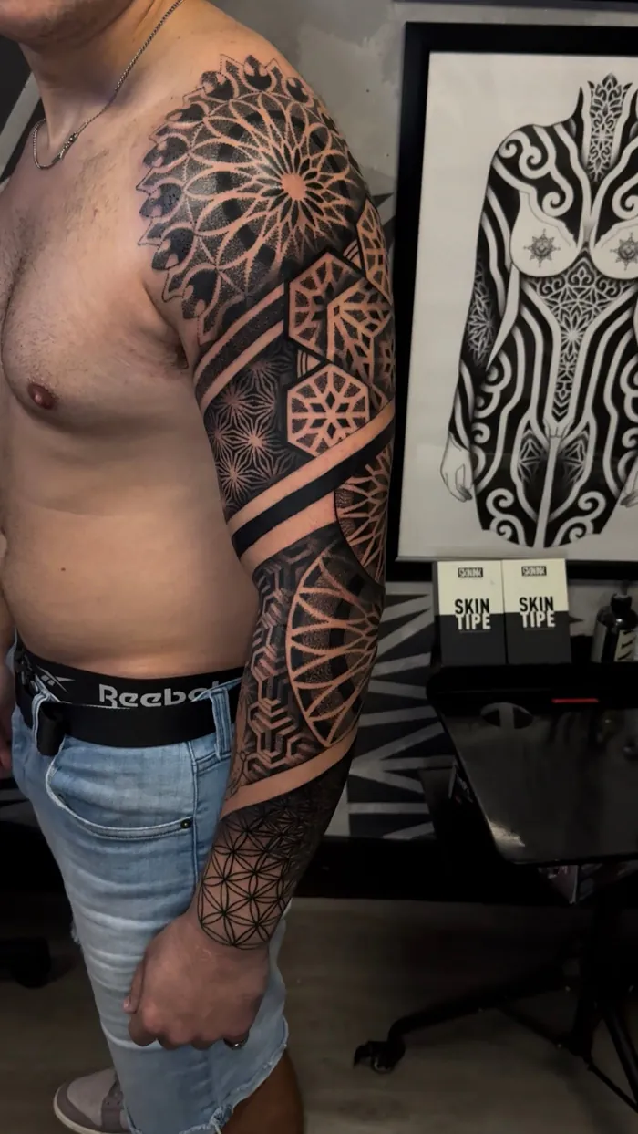 Geometric arm sleeve and chest tattoo with flower of life, mandala and dotwork bands by Duk Tattoo, Boca Raton, Florida
