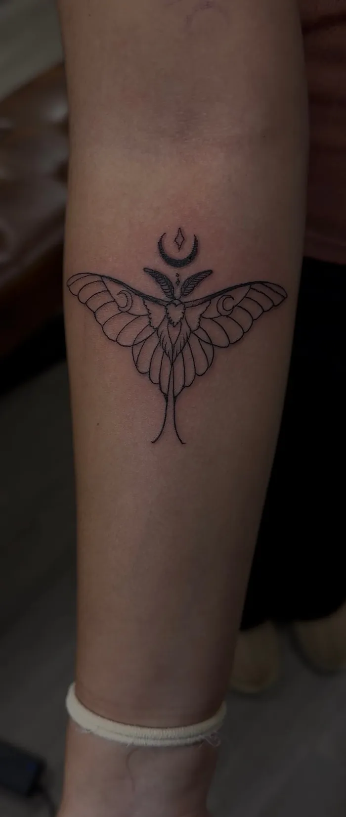 Fine line ankle tattoo of a luna moth with a crescent moon by Duk Tattoo, Boca Raton, Florida