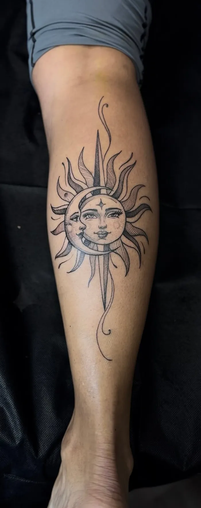 Fine line forearm tattoo of a sun and moon with faces in black and grey by Duk Tattoo, Boca Raton, Florida