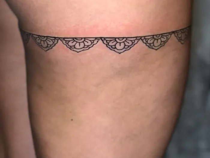 Fine line lace garter tattoo with small mandala scallops around the thigh by Duk Tattoo, Boca Raton, Florida