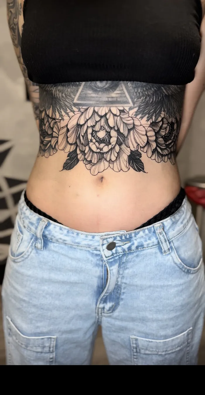 Fine line underbust tattoo with ornamental lace and peony flowers in black and grey on a woman by Duk Tattoo, Boca Raton, Florida