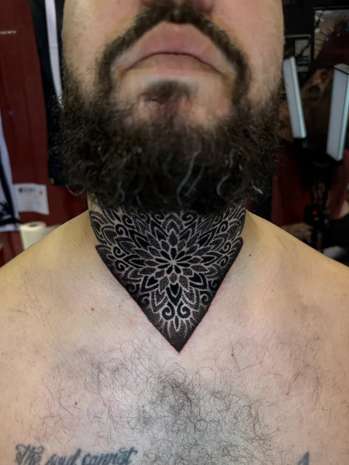 Front neck mandala tattoo in black dotwork with a V shape down the chest by Duk Tattoo, Boca Raton, Florida