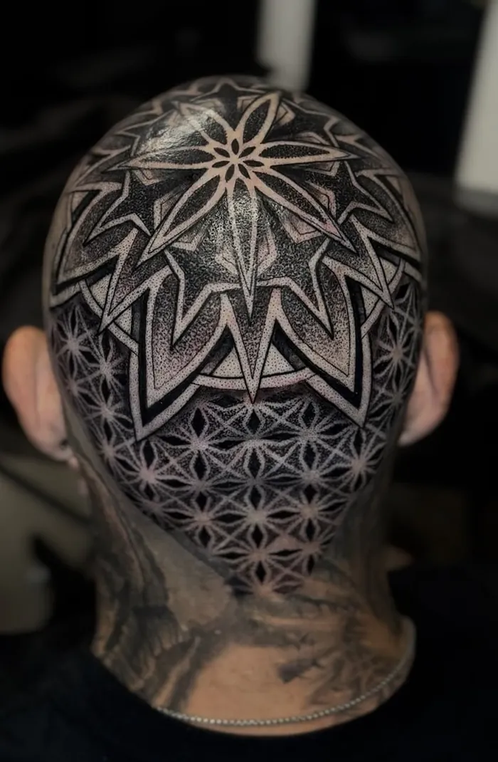 Head tattoo with a large star mandala over a flower of life pattern in black dotwork on the back of the head by Duk Tattoo, Boca Raton, Florida