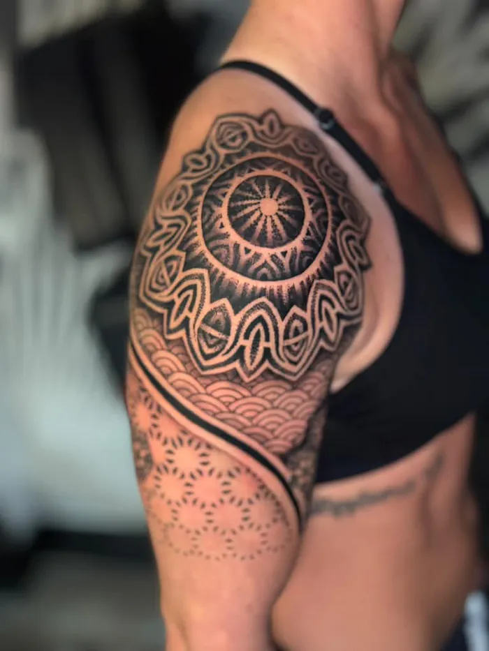 Ornamental shoulder mandala tattoo with flower of life pattern on a woman, black and grey dotwork by Duk Tattoo, Florida