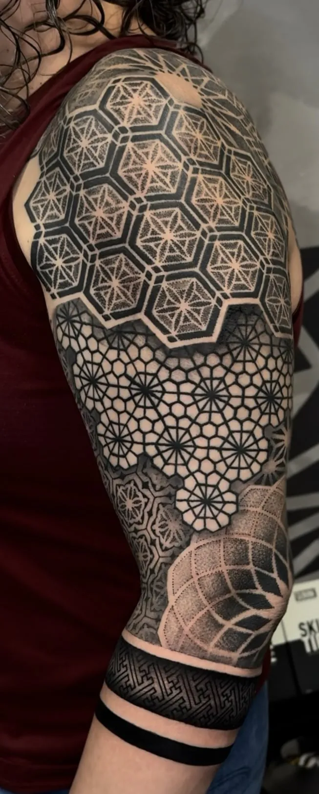 Geometric arm sleeve tattoo with hexagon flower of life on the shoulder, honeycomb pattern, dotwork sphere and black bands by Duk Tattoo, Boca Raton, Florida