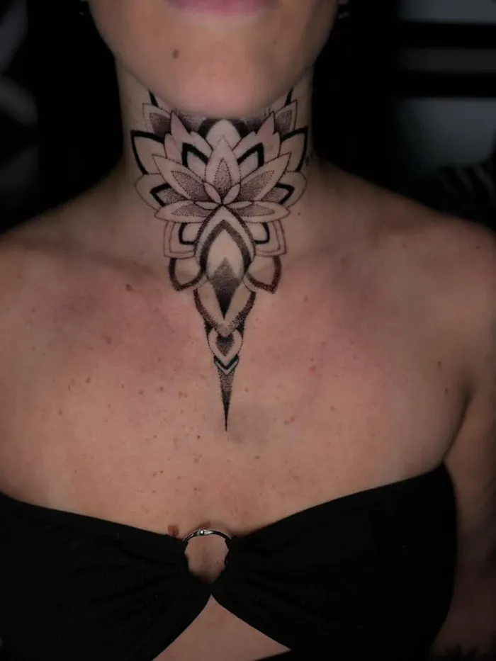 Ornamental lotus chest piece tattoo on the throat of a woman in fine black dotwork by Duk Tattoo, Boca Raton, Florida