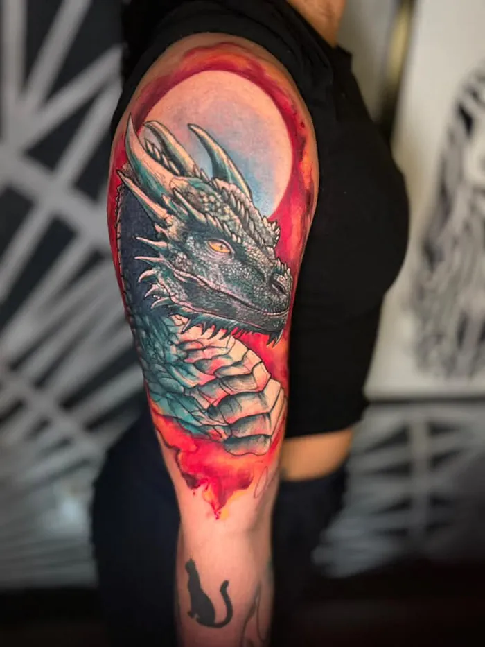 Color realism dragon tattoo on the upper arm with a red background by Duk Tattoo, Boca Raton, Florida