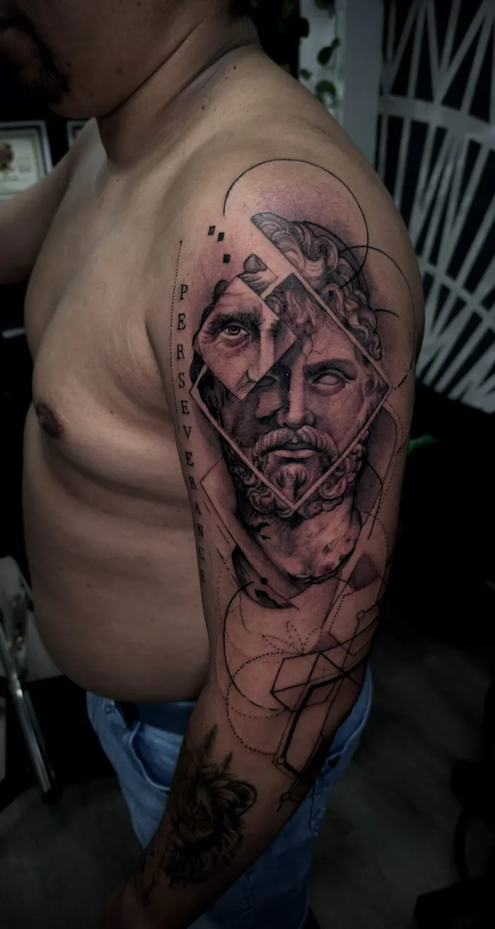 Black and grey upper arm tattoo of a Greek statue portrait with geometric lines and the word Persevere by Duk Tattoo, Boca Raton, Florida