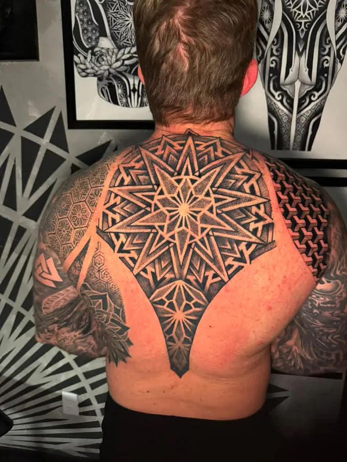 Upper back sacred geometry tattoo with a star mandala and dotwork patterns in black and grey by Duk Tattoo, Boca Raton